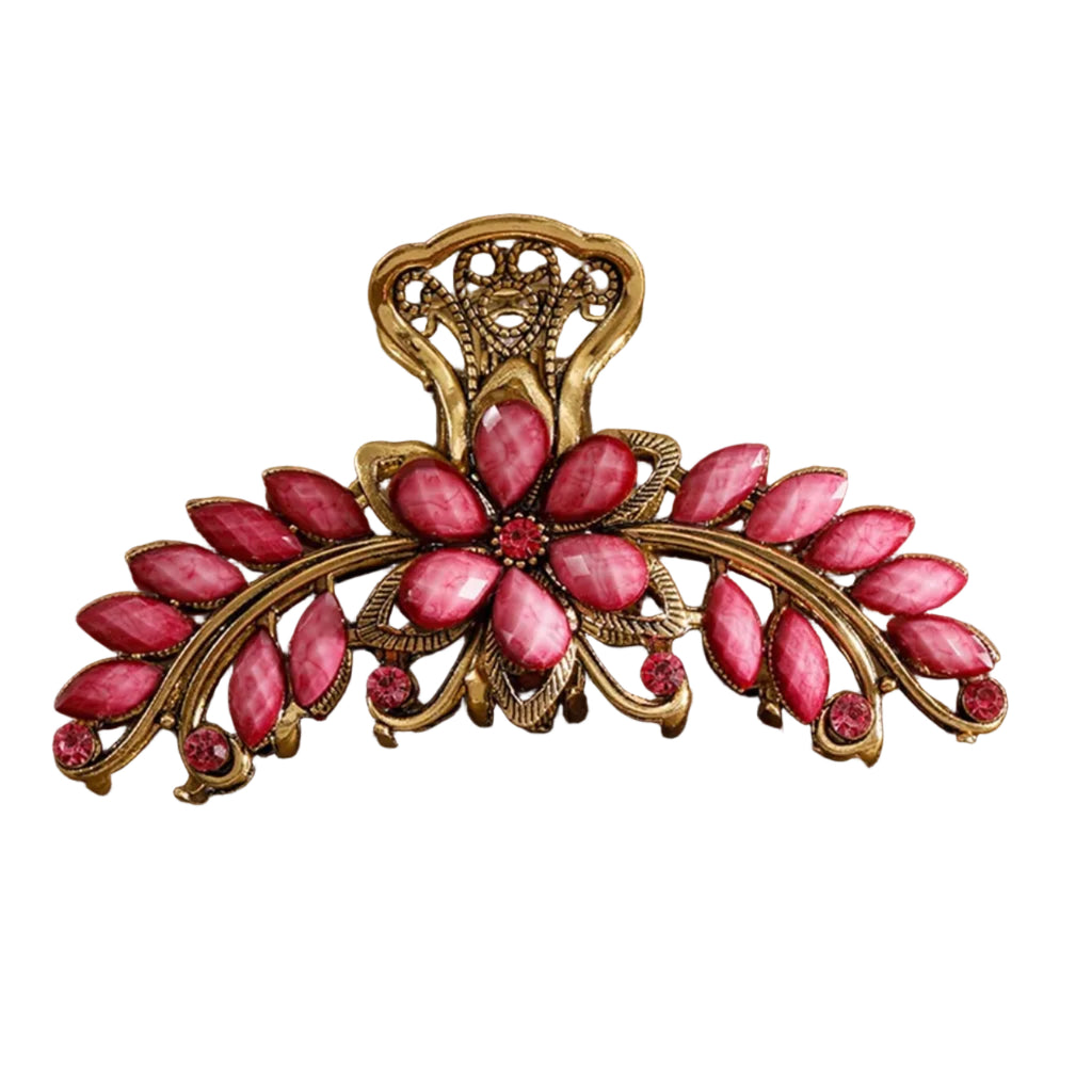 Decorative hair clip with pink stones and gold accents on a brown background