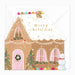 A Christmas greeting card featuring a gingerbread house with pink windows, a green wreath, snow-covered roof, gold 'merry christmas' text, a snowman, and colorful eggs, shown with a white envelope behind it.