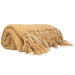Yellow throw blanket with white polka dots and fringes on a white background