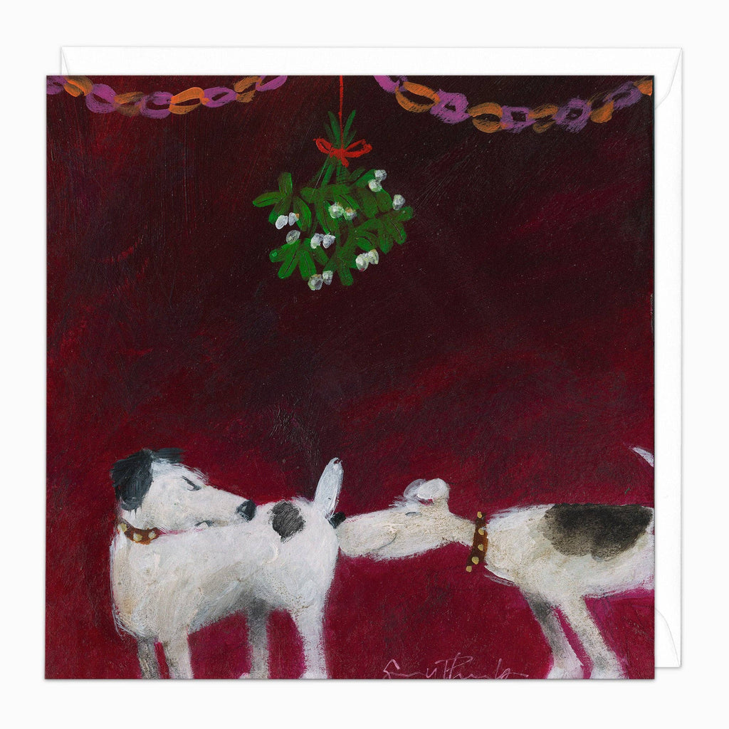 A square art print or card featuring a painted holiday scene with two dogs at the bottom, a hanging mistletoe ornament above, and a dark red background. A white sheet or border is visible around the print.