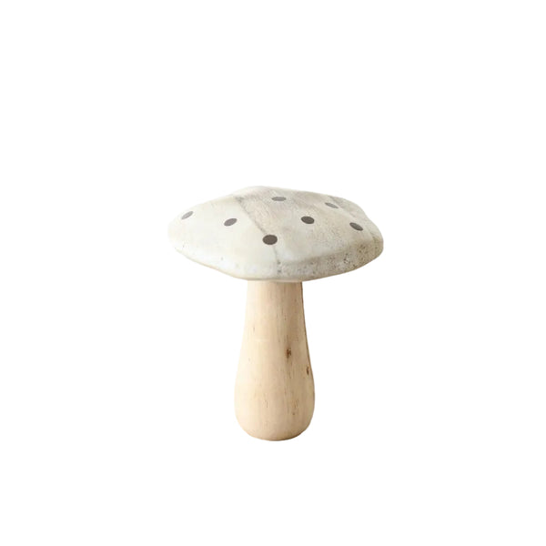 A small mushroom-shaped decorative object with a light beige cap marked with dark spots and a natural light wood stem, standing on a rustic wooden surface against a plain white background.