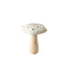 A small mushroom-shaped decorative object with a light beige cap marked with dark spots and a natural light wood stem, standing on a rustic wooden surface against a plain white background.