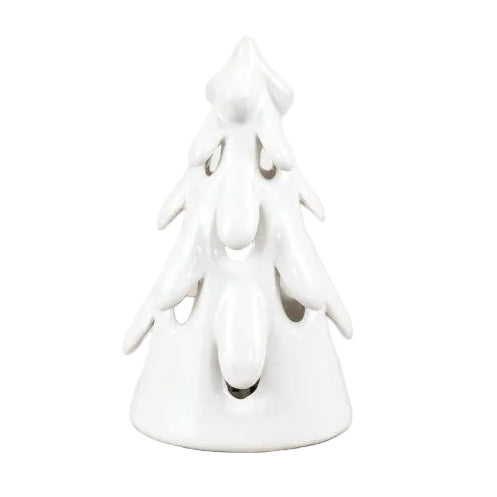 A small white ceramic Christmas tree candle holder with layered branches and a tiered base, shown on a light wood surface against a plain off-white background.