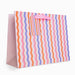 Colorful striped gift bag with a pink handle on a white background