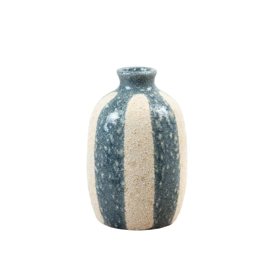 A small handmade ceramic bottle with a dark speckled glaze and a vertical beige stripe, sitting on a light wooden surface against a white background.