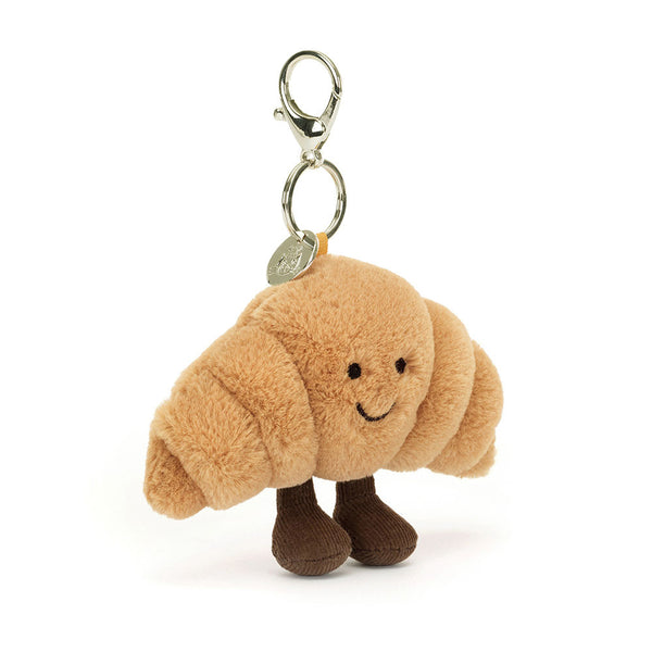 Plush croissant-shaped keychain with a tag on a white background
