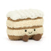 Plush toy resembling a layered dessert with white cream and brown layers on a white background