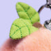 Green leaf-shaped keychain against a light purple background