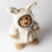 Stuffed teddy bear wearing a white bunny costume on a light background