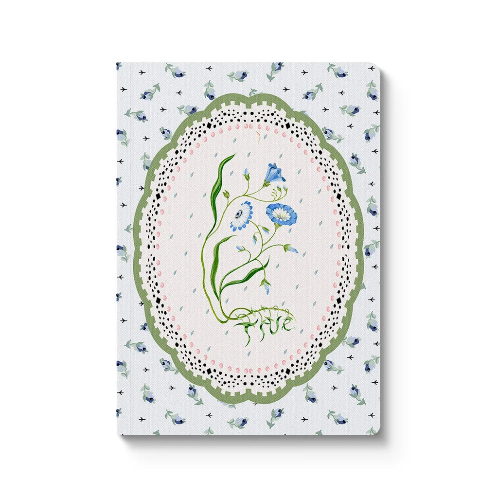 Notebook with floral design on a wooden surface with lavender and eucalyptus leaves.