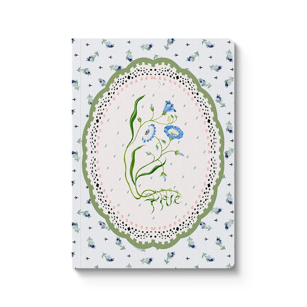Notebook with floral design on a wooden surface with lavender and eucalyptus leaves.
