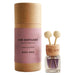A car diffuser bottle with two wooden scent sticks and a clear glass base stands beside its kraft paper cylindrical packaging. The label is dusty pink with black text reading 'CAR DIFFUSER BLACK ORCHID Luxurious & Bold ROSY ROO'.