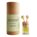 A car diffuser set by Rosy Roo, featuring a cylindrical kraft paper tube with a pale green label next to a small glass bottle with yellow liquid and two wooden diffuser sticks, set on a light surface with a blurred vase in the background.