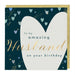 A square birthday card with a gold envelope behind it. The card has a dark teal background decorated with small pastel hearts and gold confetti, featuring a large white heart shape and the text 'to my amazing Husband on your birthday' in teal and gold lettering.