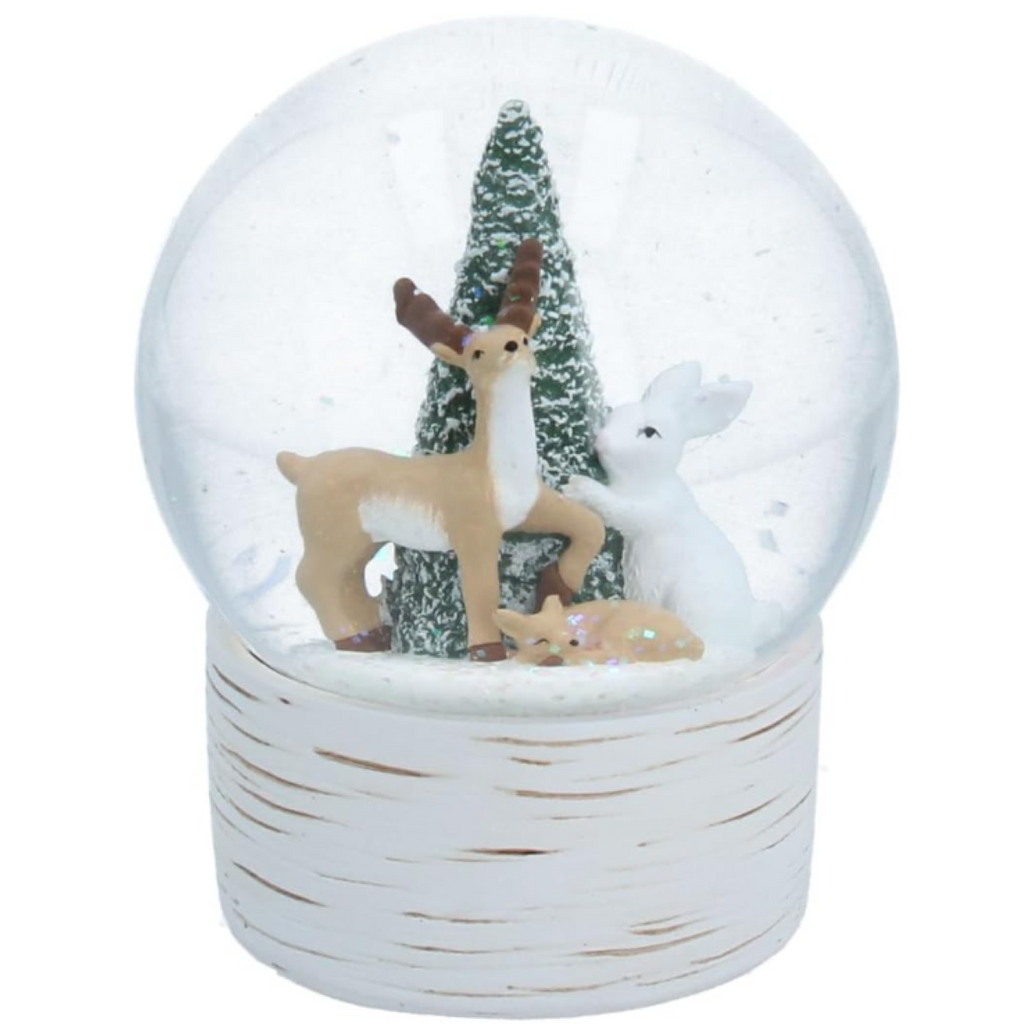 A decorative snow globe figurine with a clear round dome, white textured base, and winter scene featuring a tan deer, a white deer, a small green tree, and glittery white snow.