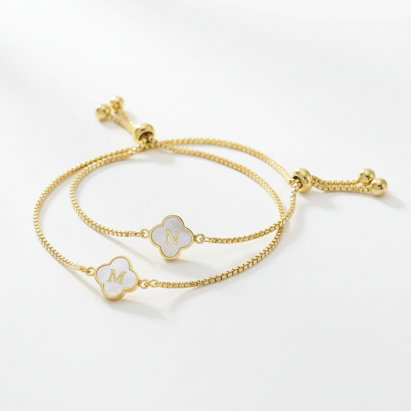 Gold bracelet with clover-shaped charms on a white background
