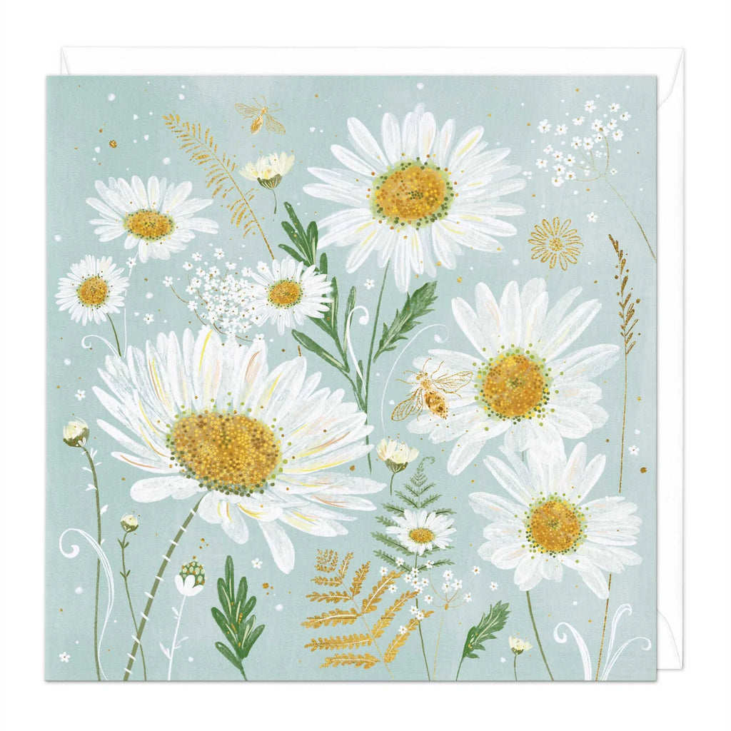 A square art print or card featuring a botanical illustration of white daisies with yellow centers, green leaves, small bees, and delicate wildflowers on a pale blue background, with a white envelope partially visible behind it.