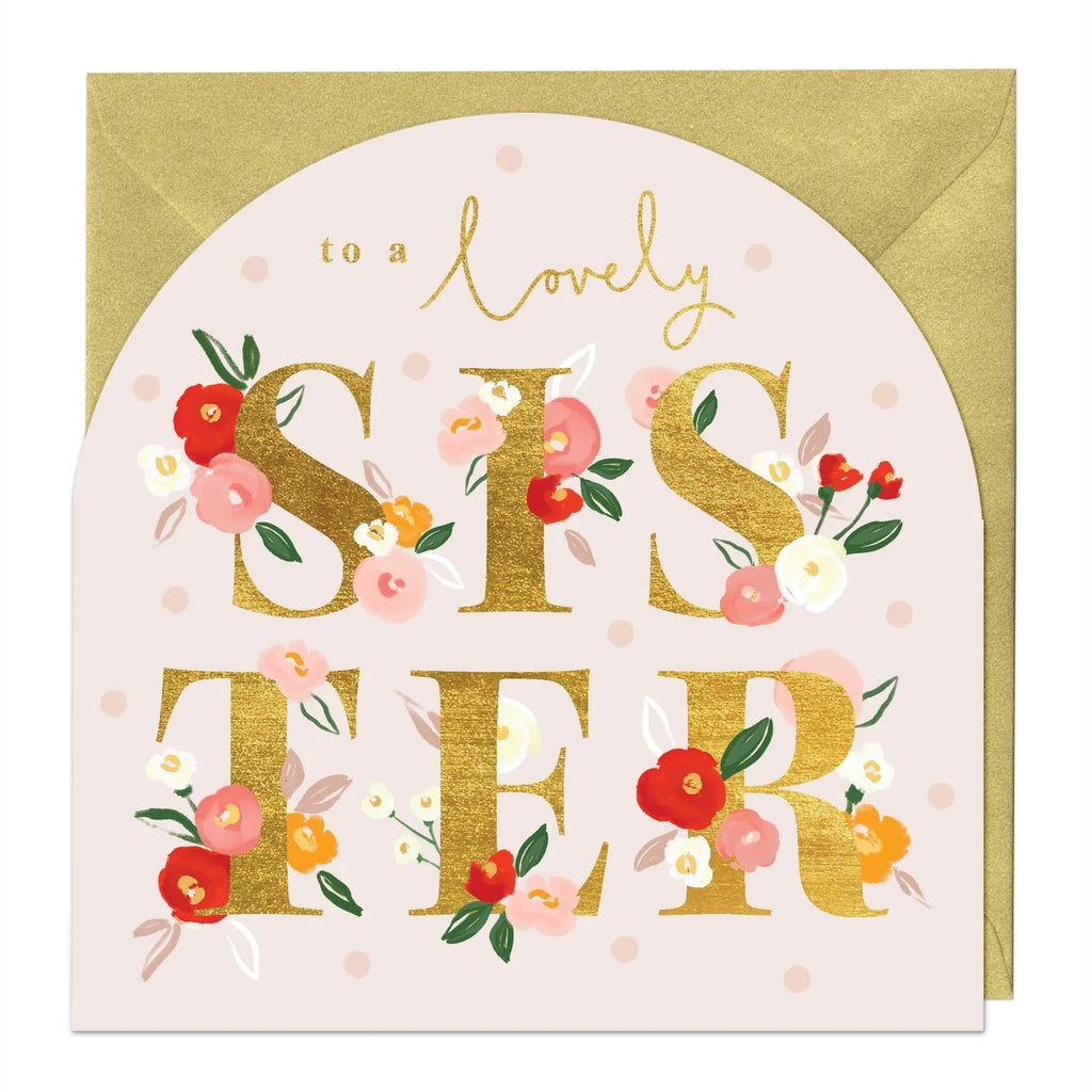 A square greeting card with a gold envelope behind it. The card has a pale blush background with a large arched design featuring the words 'to a lovely sister' in gold script and block lettering, decorated with red, pink, orange, and white flowers with green leaves.