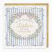 A square birthday card with a gold envelope behind it. The card has a white border, light blue vertical stripes, and a central cream circle with the text 'TO MY WONDERFUL Sister ON YOUR BIRTHDAY' in black and gold script.