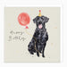 Birthday card with a black dog holding a red balloon and wearing a party hat on a beige background.