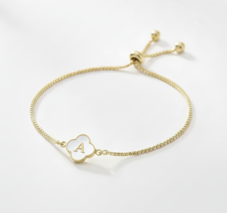 Gold bracelet with a small round charm featuring the letter 'A' on a white background
