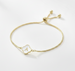 Gold bracelet with a small round charm featuring the letter 'A' on a white background