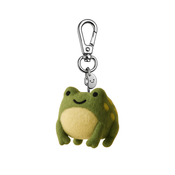Plush frog keychain with a smiley face charm on a white background