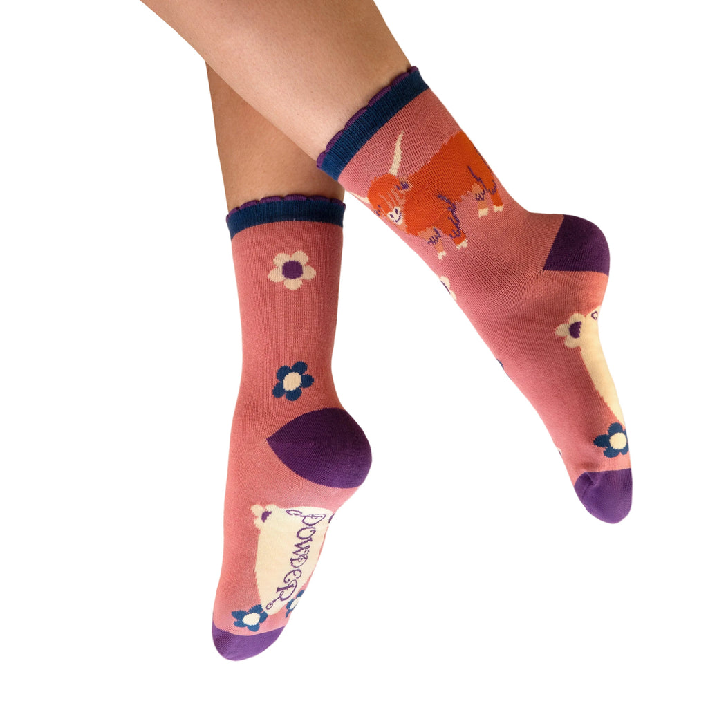 Colorful socks with floral designs worn by a person on a white background
