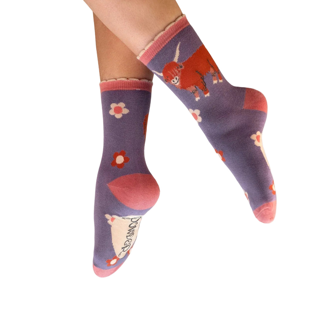 Purple socks with cartoon designs worn by a person on a white background