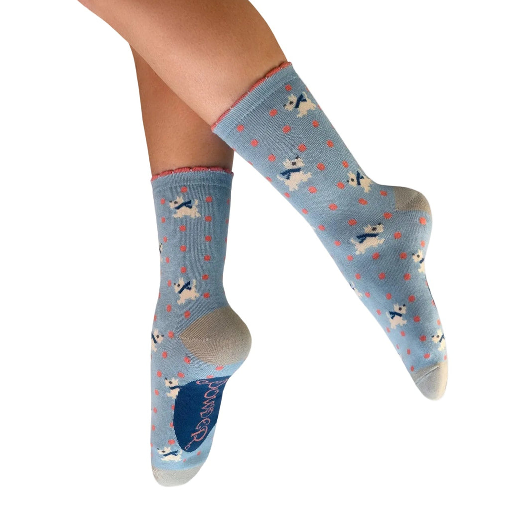 Light blue socks with dog pattern worn by a person on a white background