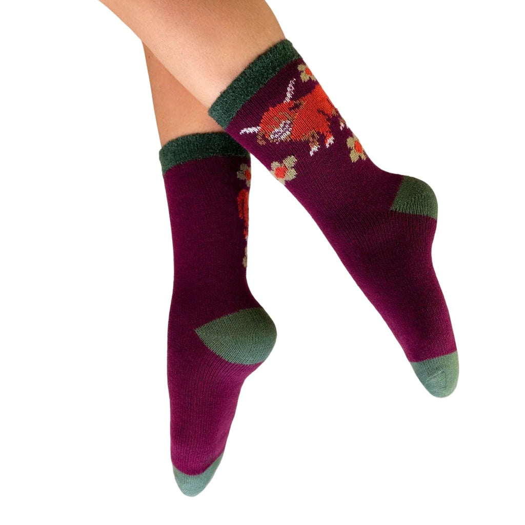 Purple socks with green accents worn by a person on a white background