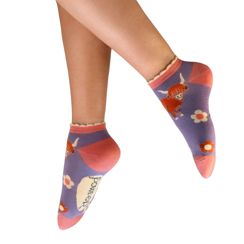 Colorful socks with cartoon characters worn by a person on a white background