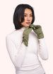 Woman wearing a white turtleneck and green gloves on a plain background