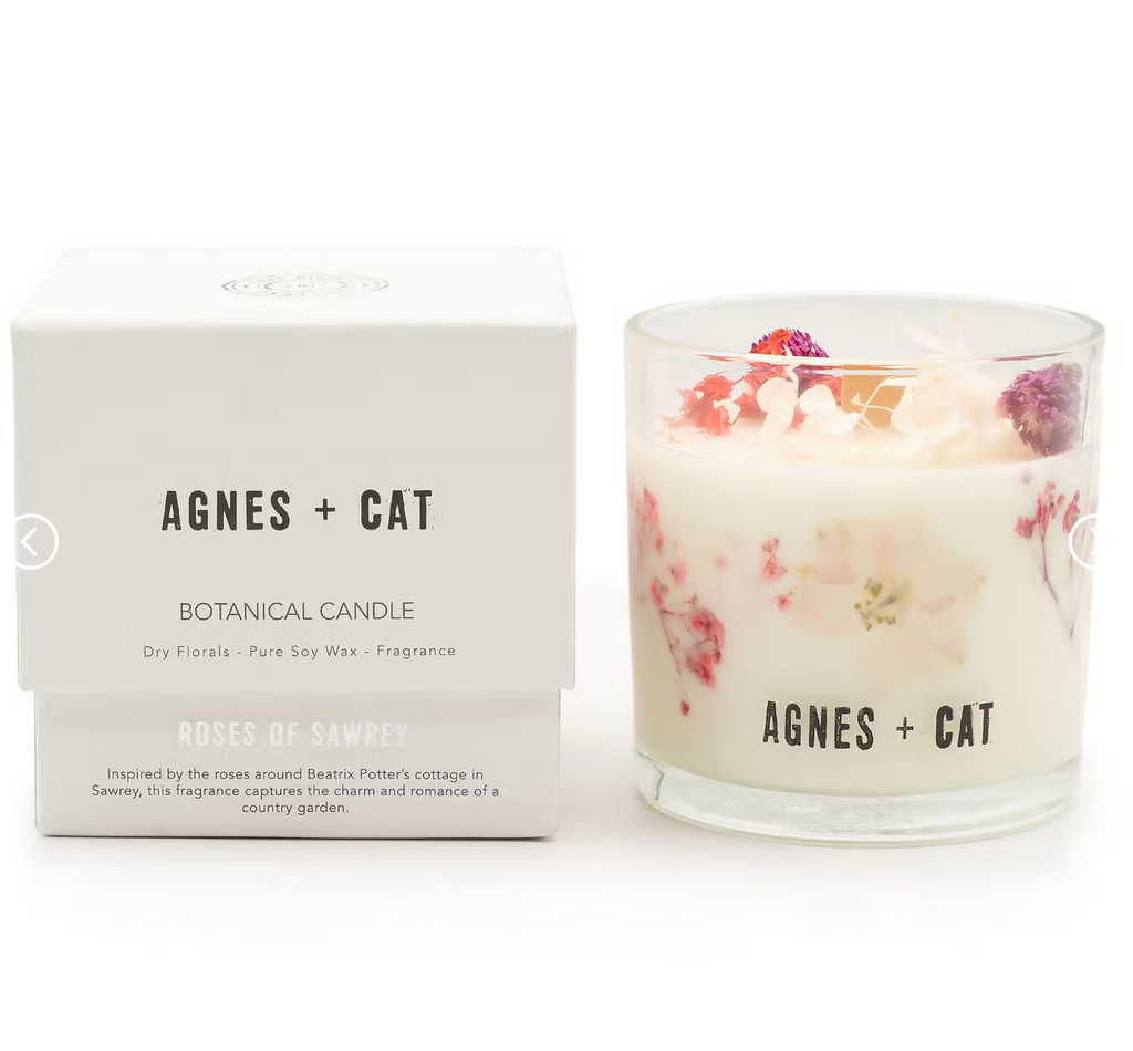 Botanical candle with floral design and 'Agnes + Cat' branding next to its packaging on a white background.