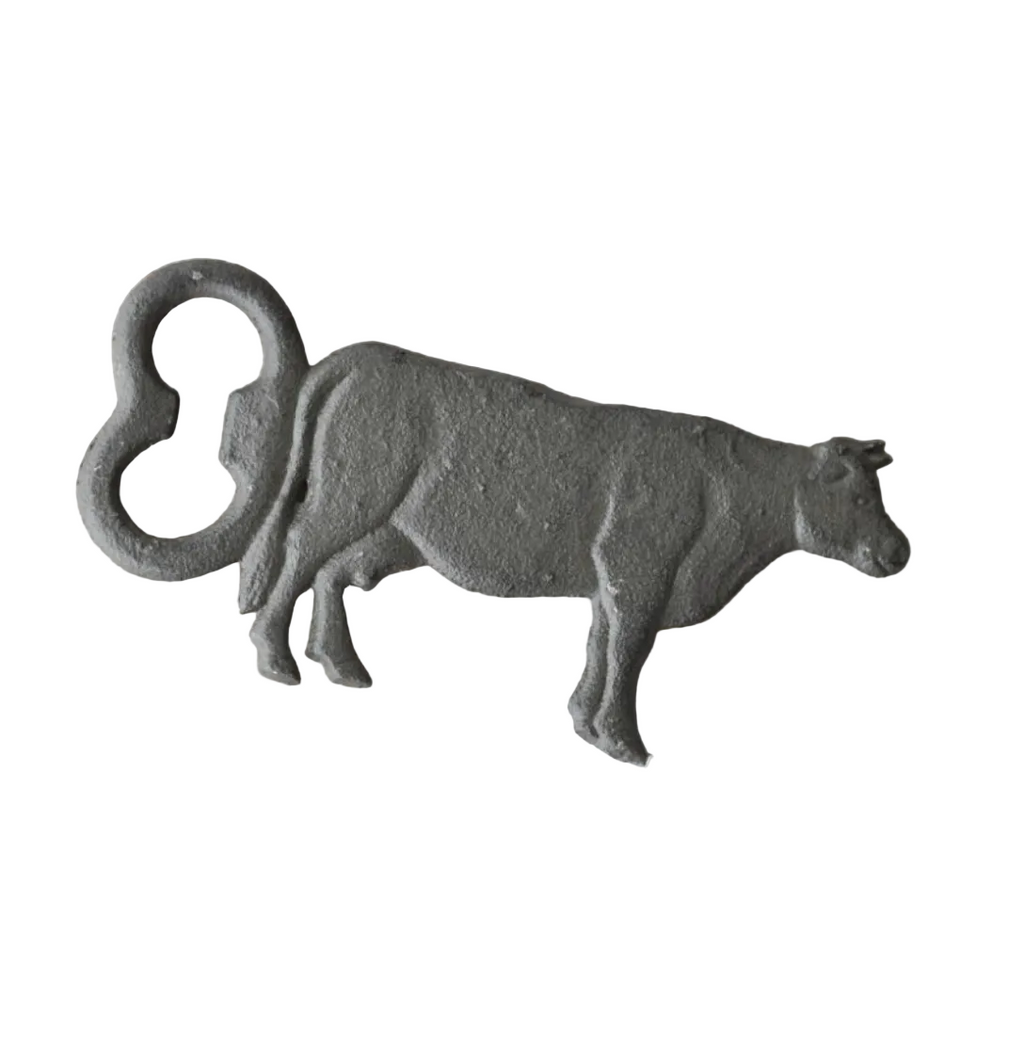 Cast iron cow bottle opener on a white background.