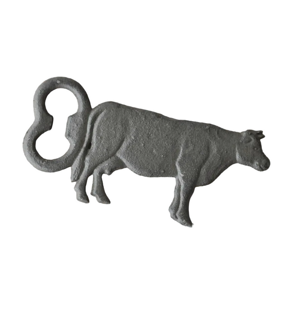 Cast iron cow bottle opener on a white background.