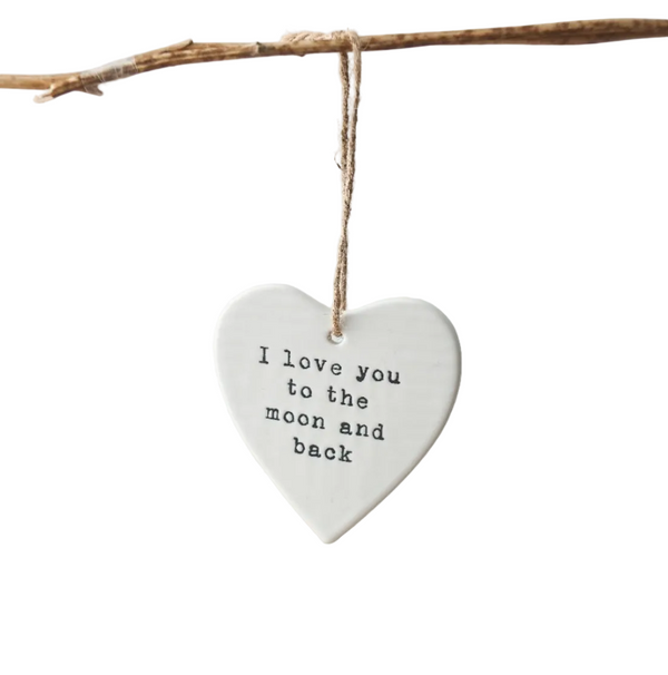 Heart-shaped ceramic plaque with 'I love you to the moon and back' text, hanging on a branch.