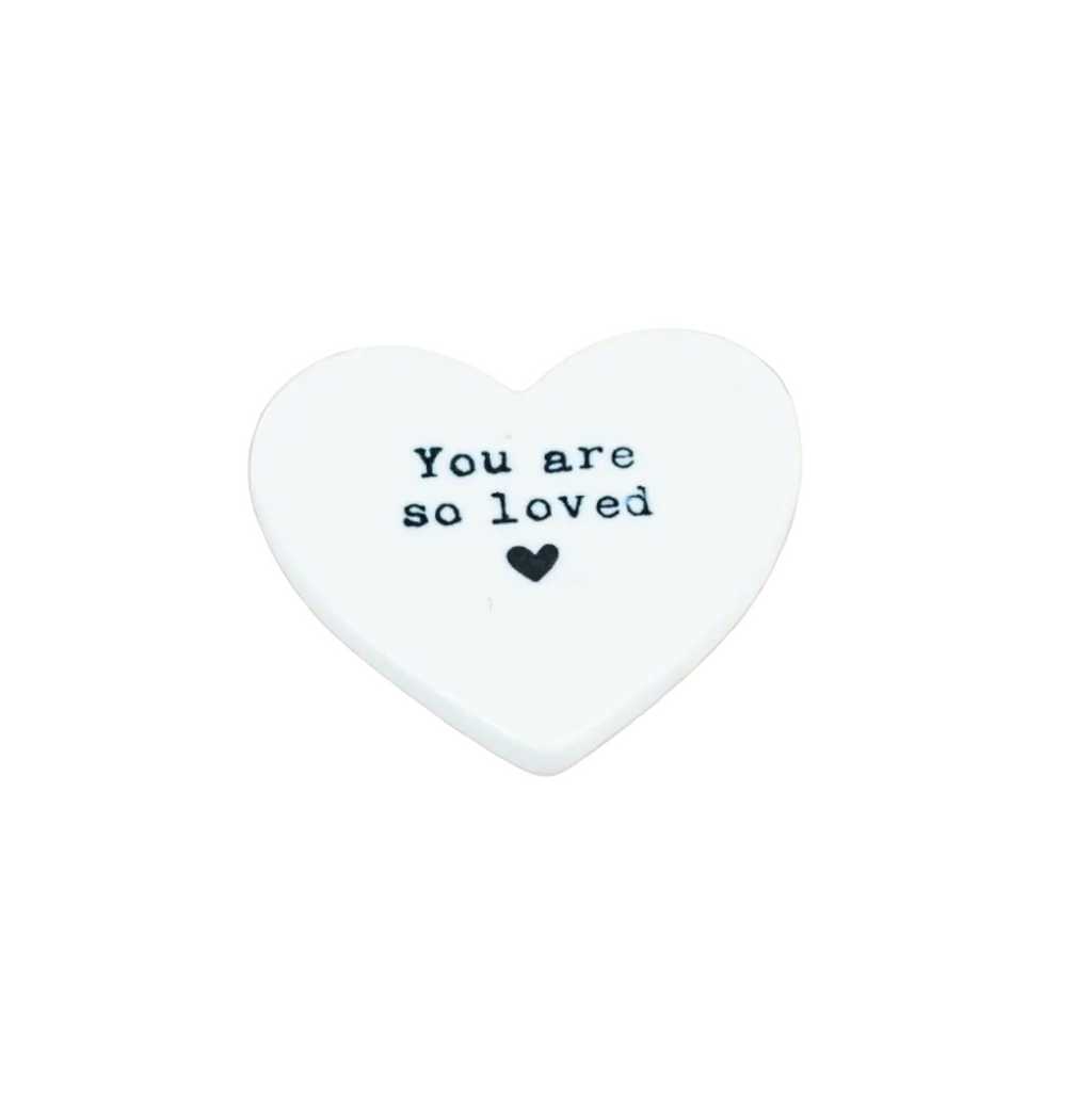 Heart-shaped white stone with 'You are so loved' text on a white background