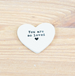 Heart-shaped white stone with 'You are so loved' text on a beige background