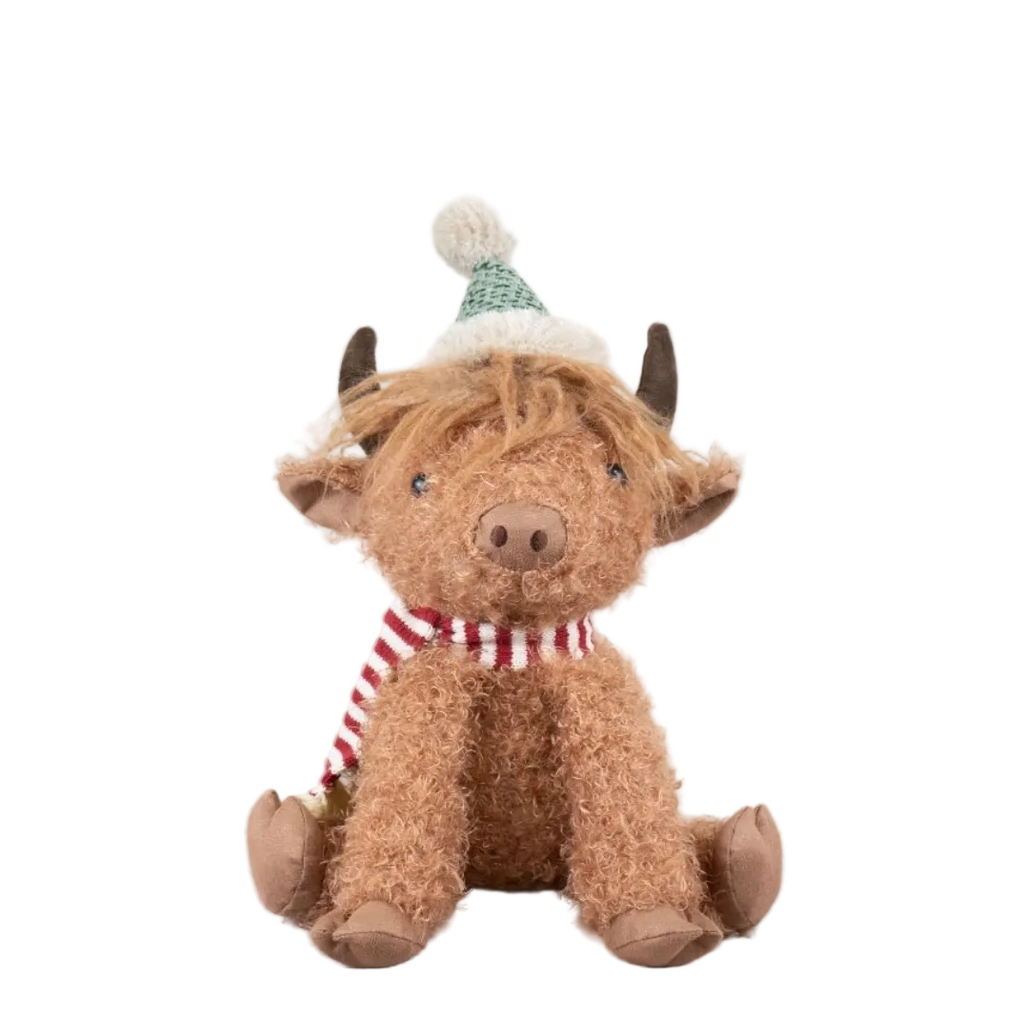 Plush toy cow wearing a festive hat and scarf on a white background