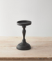 Black candle holder on a wooden surface with a white background
