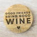 Wooden coaster with 'Good friends bring good wine' text on a white background