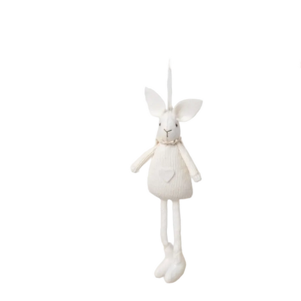 White plush toy hanging from a wooden rod on a white wall background