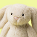 Plush bunny toy with a light gray color on a yellow background
