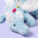 Close-up of a blue plush toy with a white ears on a light purple background