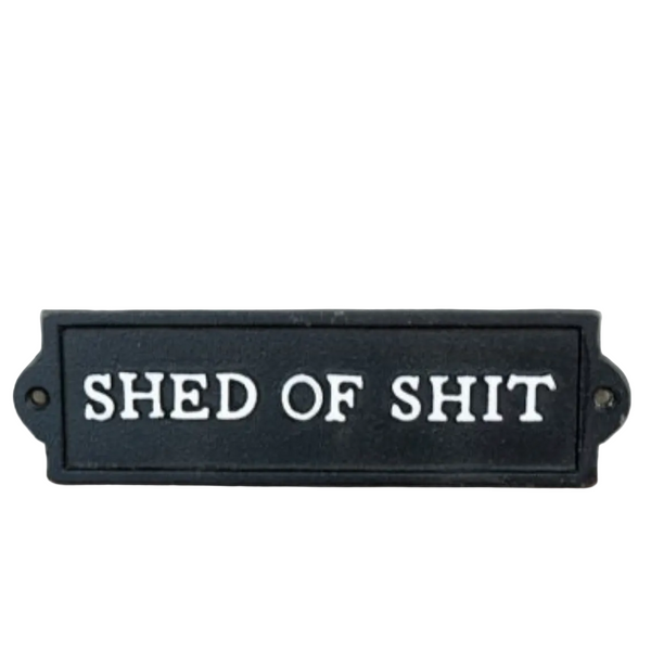 Black sign with white text 'SHED OF SHIT' on a white surface.