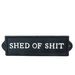Black sign with white text 'SHED OF SHIT' on a white surface.