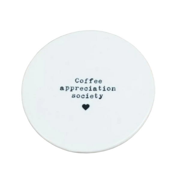 Round white coaster with 'Coffee appreciation society' text on a white surface