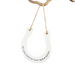 Round white sign with text 'All you need is love and a horse' hanging on a white surface.