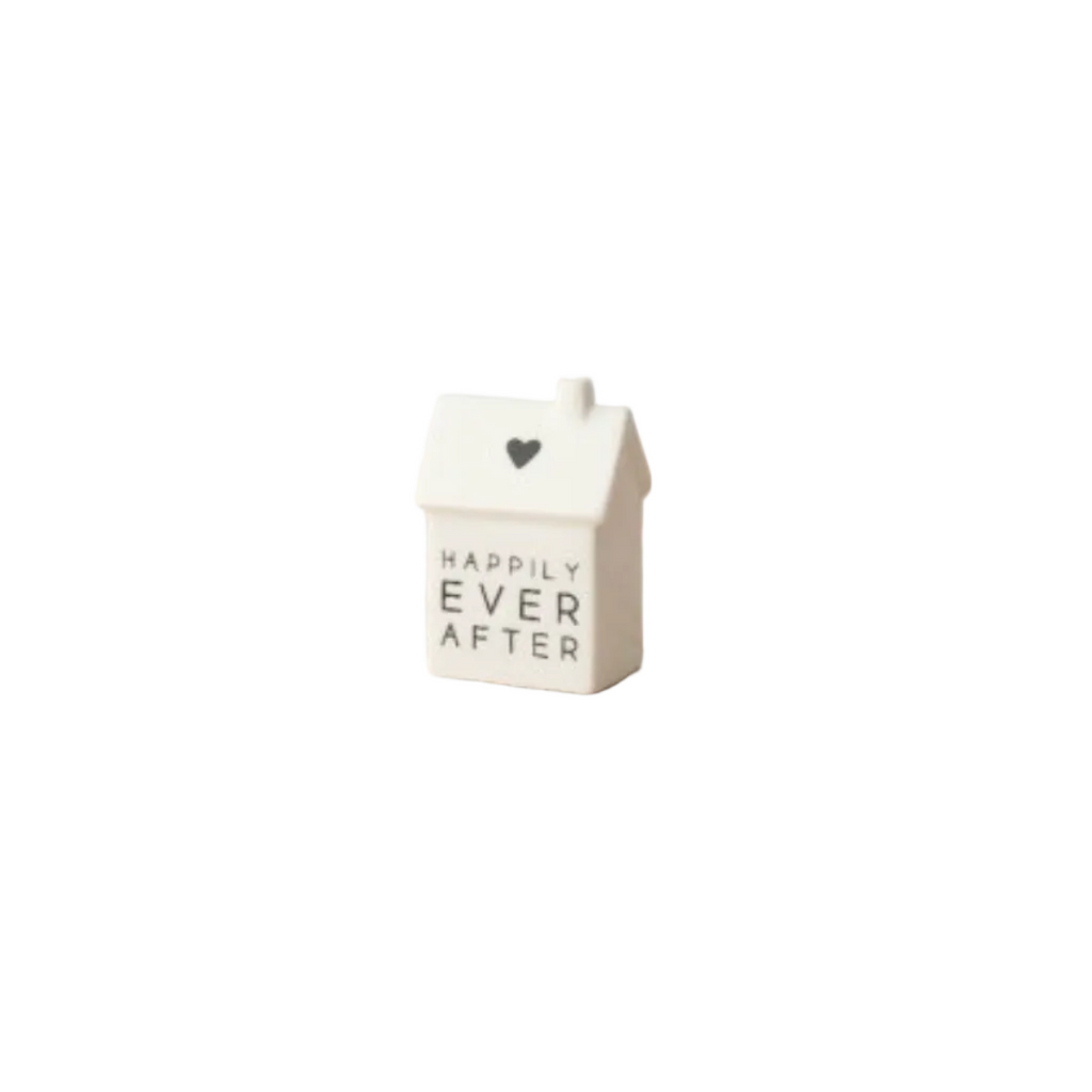Small white ceramic house-shaped object with 'Happily Ever After' text on a white surface.